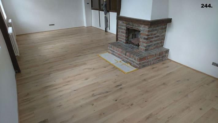 Ein Wohnzimmer mit Holzboden und gemauertem Kamin.