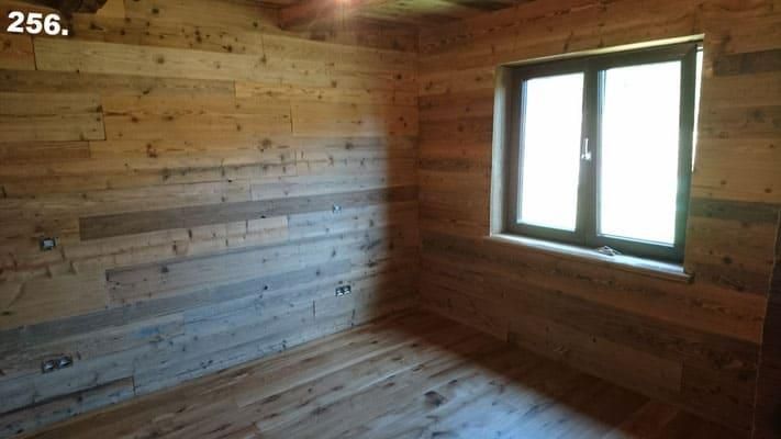 Ein leerer Raum mit Wänden und Böden aus Holz und zwei Fenstern.