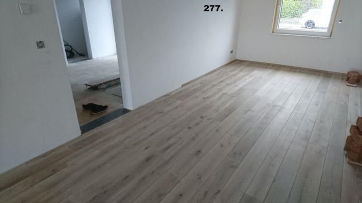 Ein leerer Raum mit Holzboden und weißen Wänden.