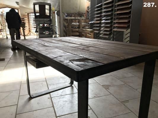 Ein Holztisch mit Metallrahmen steht auf einem gefliesten Boden.
