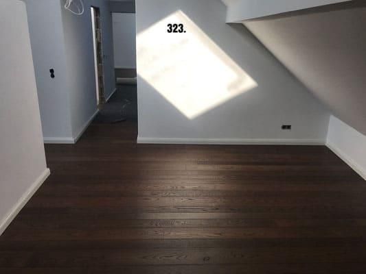 Ein Raum mit Holzboden und einem Fenster mit der Nummer 323 darauf.