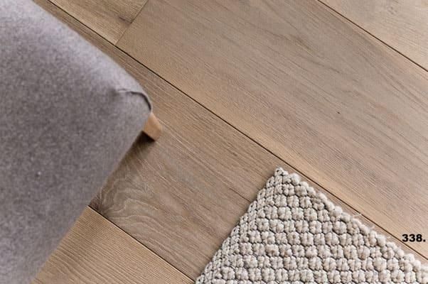 Auf einem Holzboden liegt neben einem Stuhl ein Teppich.