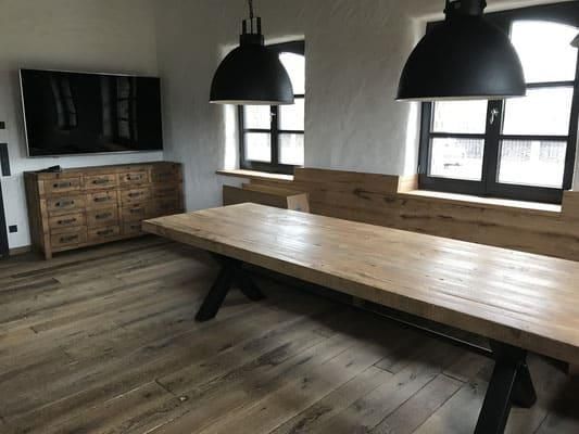 Ein Holztisch und eine Bank in einem Raum mit zwei Fenstern.
