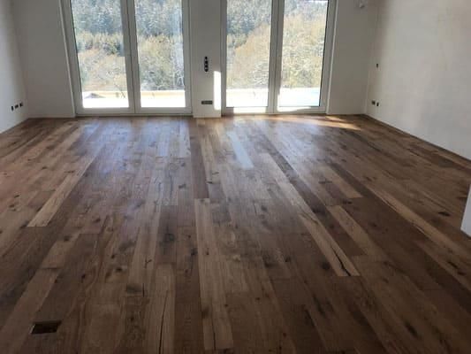 Ein Wohnzimmer mit Holzboden und vielen Fenstern.
