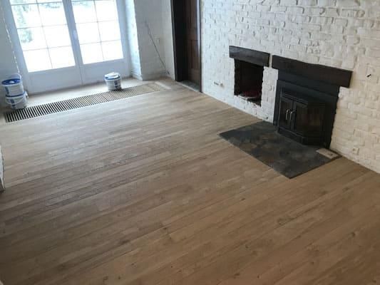 Ein Wohnzimmer mit Holzboden und Kamin.