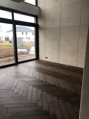 Ein leerer Raum mit Holzboden und großem Fenster.