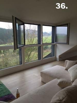 Ein Wohnzimmer mit Couch und vielen Fenstern.