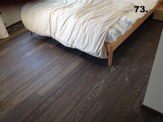 Ein Schlafzimmer mit Holzboden und einem Bett mit der Nummer 73 darauf