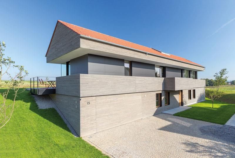 Ein modernes Haus mit rotem Dach steht auf einer üppigen grünen Wiese.