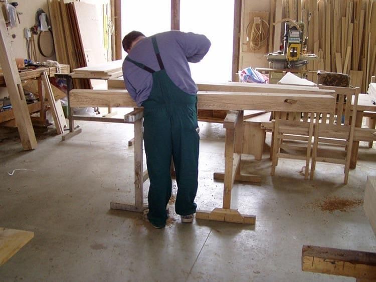 Ein Mann im Overall arbeitet an einem Stück Holz