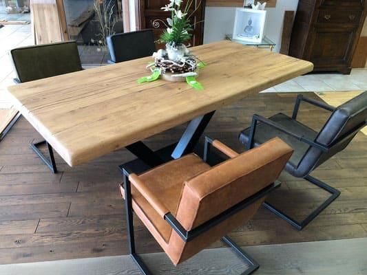 Ein Holztisch mit Stühlen und einer Vase mit Blumen darauf