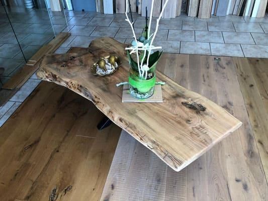 Ein Holztisch mit einer Vase mit Blumen darauf.