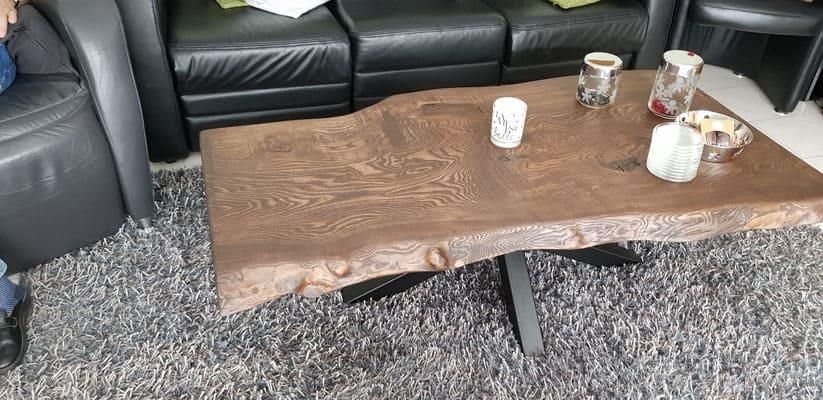 Ein Couchtisch aus Holz steht in einem Wohnzimmer neben einer Couch.