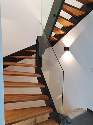 Eine Holztreppe mit einem Glasgeländer in einem Haus.