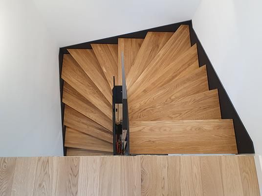 Eine hölzerne Wendeltreppe mit schwarzem Geländer und Holzboden.