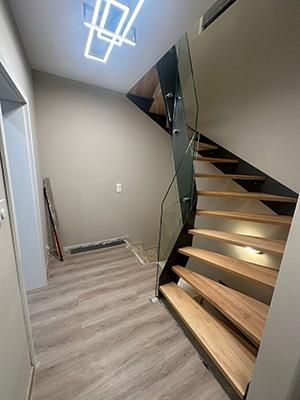 Ein Flur mit einer Holztreppe und einem Glasgeländer.