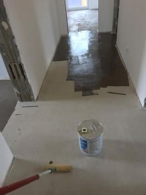 Eine Farbdose steht neben einer Farbrolle auf dem Boden.