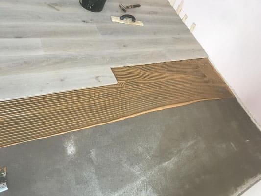 Eine Person verlegt einen Holzboden in einem Raum.