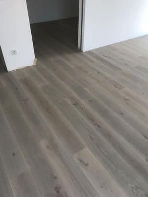 Ein Wohnzimmer mit Holzboden und einer Tür, die zu einem Flur führt.