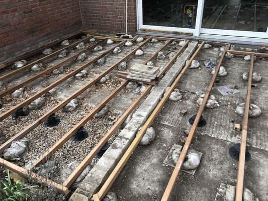 Auf einem Betonboden wird ein Holzdeck errichtet.