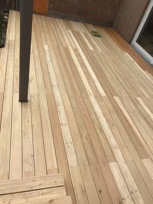 Ein Holzdeck mit einer Backsteinmauer im Hintergrund.
