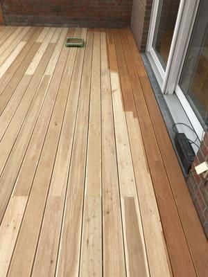 Ein Holzdeck mit einer Glasschiebetür im Hintergrund.