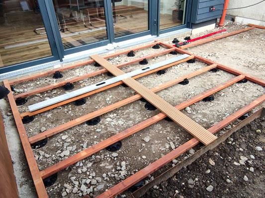 Auf einem Erdboden wird ein Holzdeck gebaut.