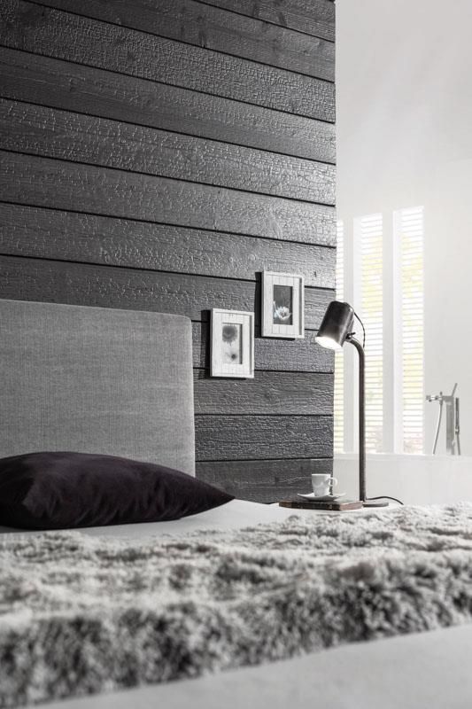 Ein Schwarzweißfoto eines Schlafzimmers mit einem Bett und einer Lampe.