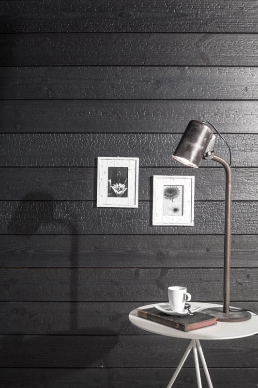 Eine Lampe steht auf einem Tisch vor einer schwarzen Wand.
