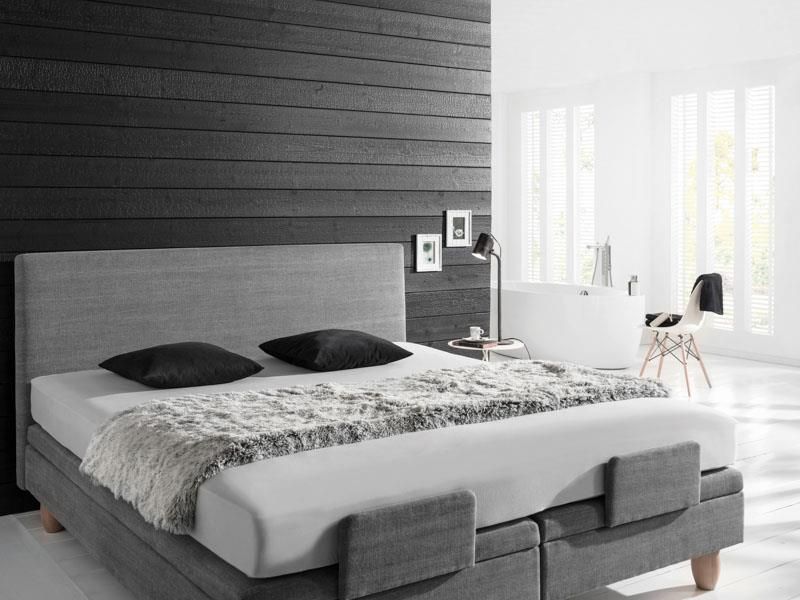 Ein Bett mit Matratze und Kissen in einem Schlafzimmer mit einer schwarzen Wand.