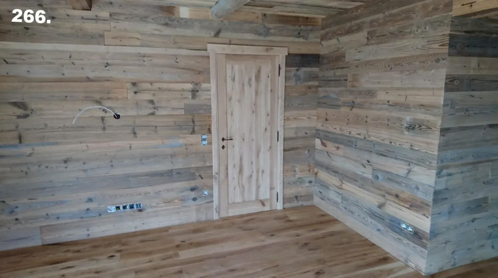 Ein Zimmer mit Holzwänden und -tür sowie Holzboden.