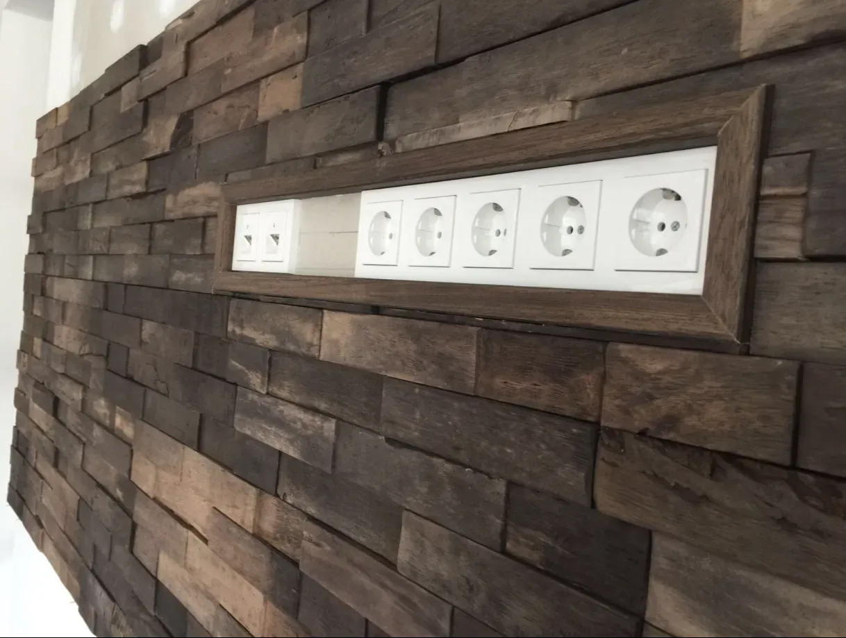 Holzwand mit einer Vertiefung, in der sich fünf weiße Steckdosen befinden.