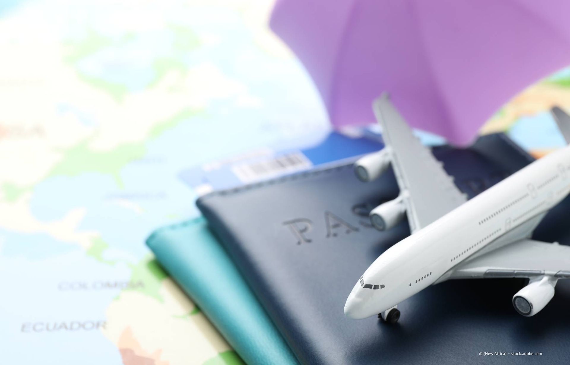 Ein Spielzeugflugzeug auf Pässen und eine Landkarte deuten auf eine Reise hin.