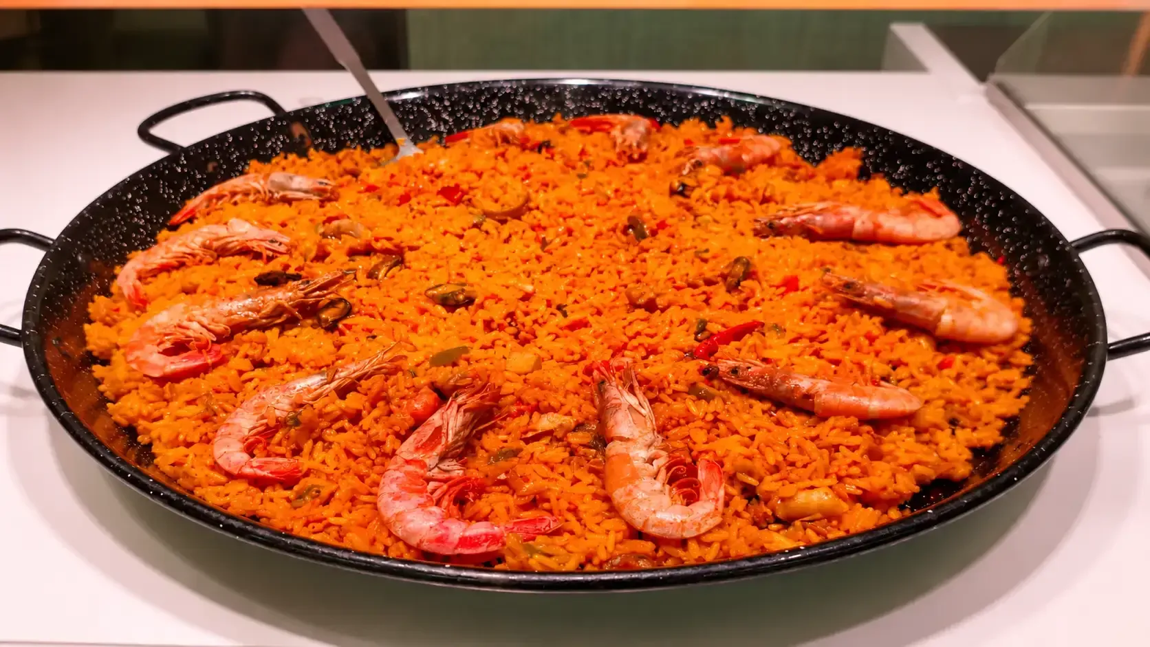 Paella de mariscos a la naranja con camarones y cangrejo en una sartén sobre la estufa.