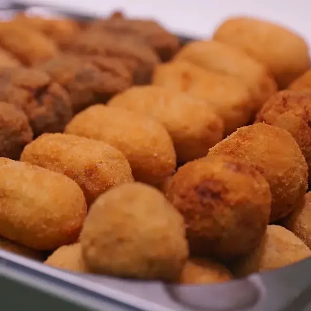 Bandeja de croquetas empanizadas doradas en una fuente para servir.