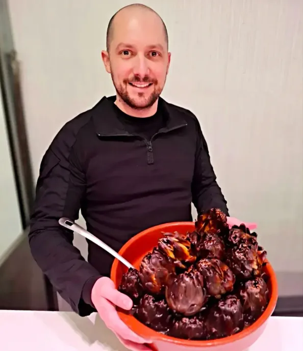 Un hombre sostiene con unas pinzas un cuenco rojo lleno de dulces cubiertos de chocolate