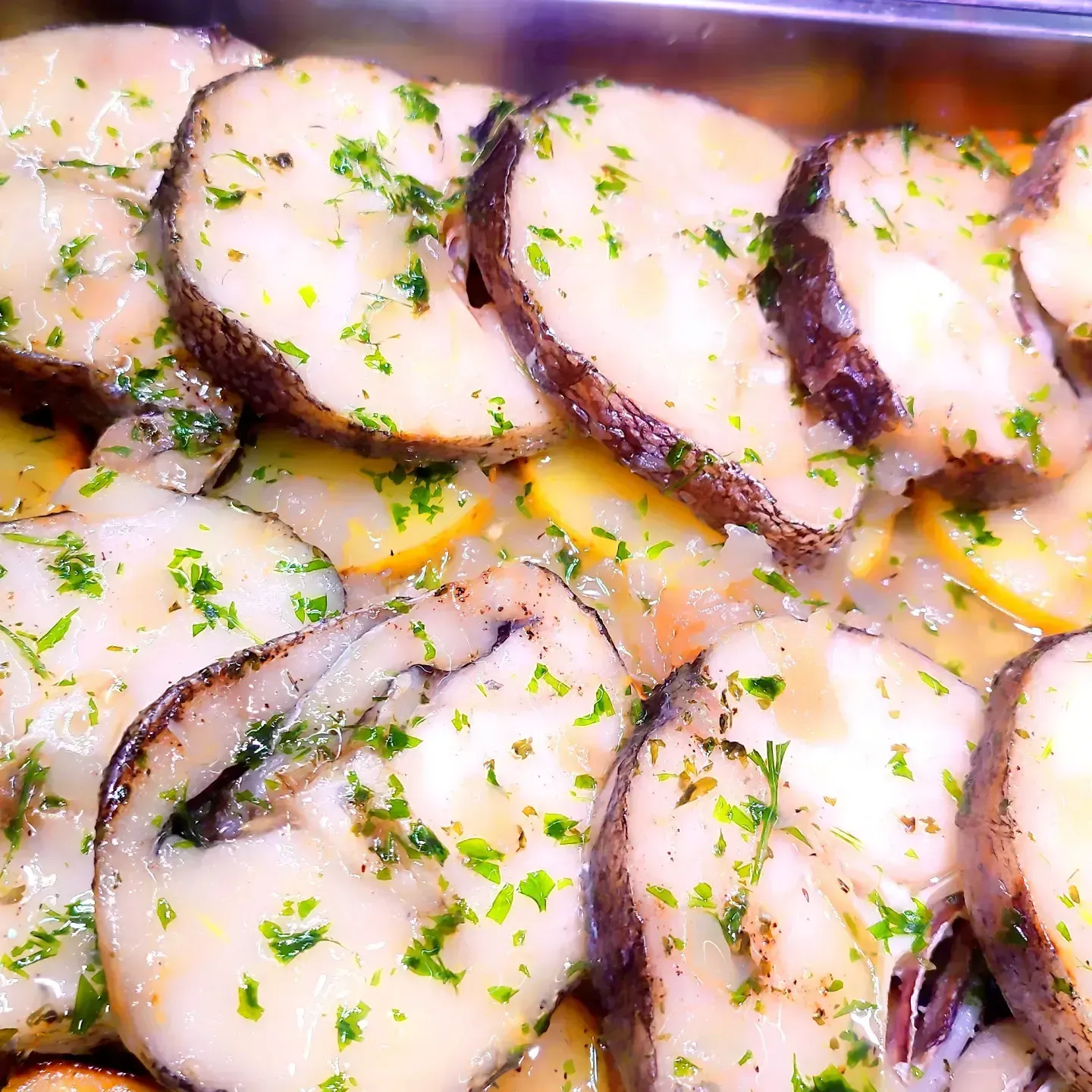 Pulpo en rodajas con hierbas en una salsa ligera, dispuesto en un plato.