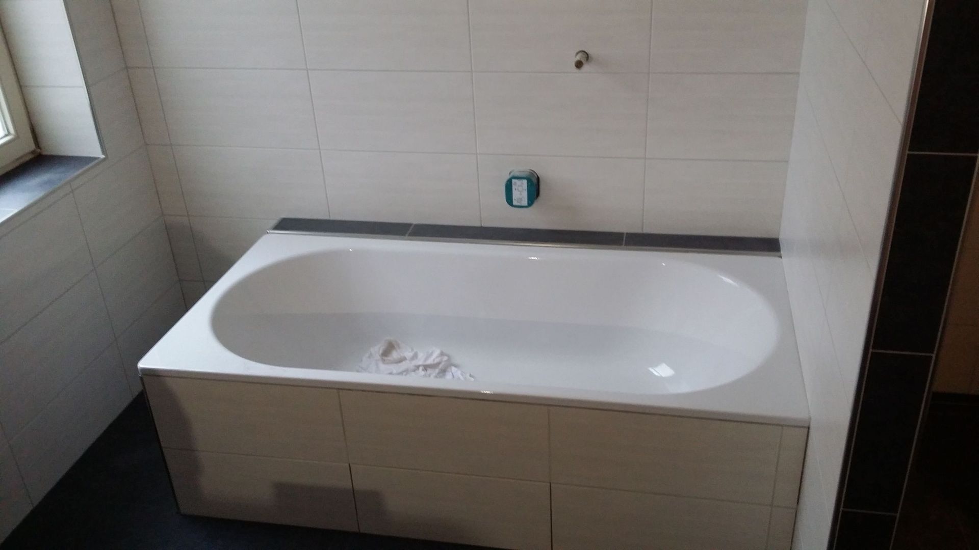 Eine weiße Badewanne steht in einem Badezimmer neben einem Fenster.