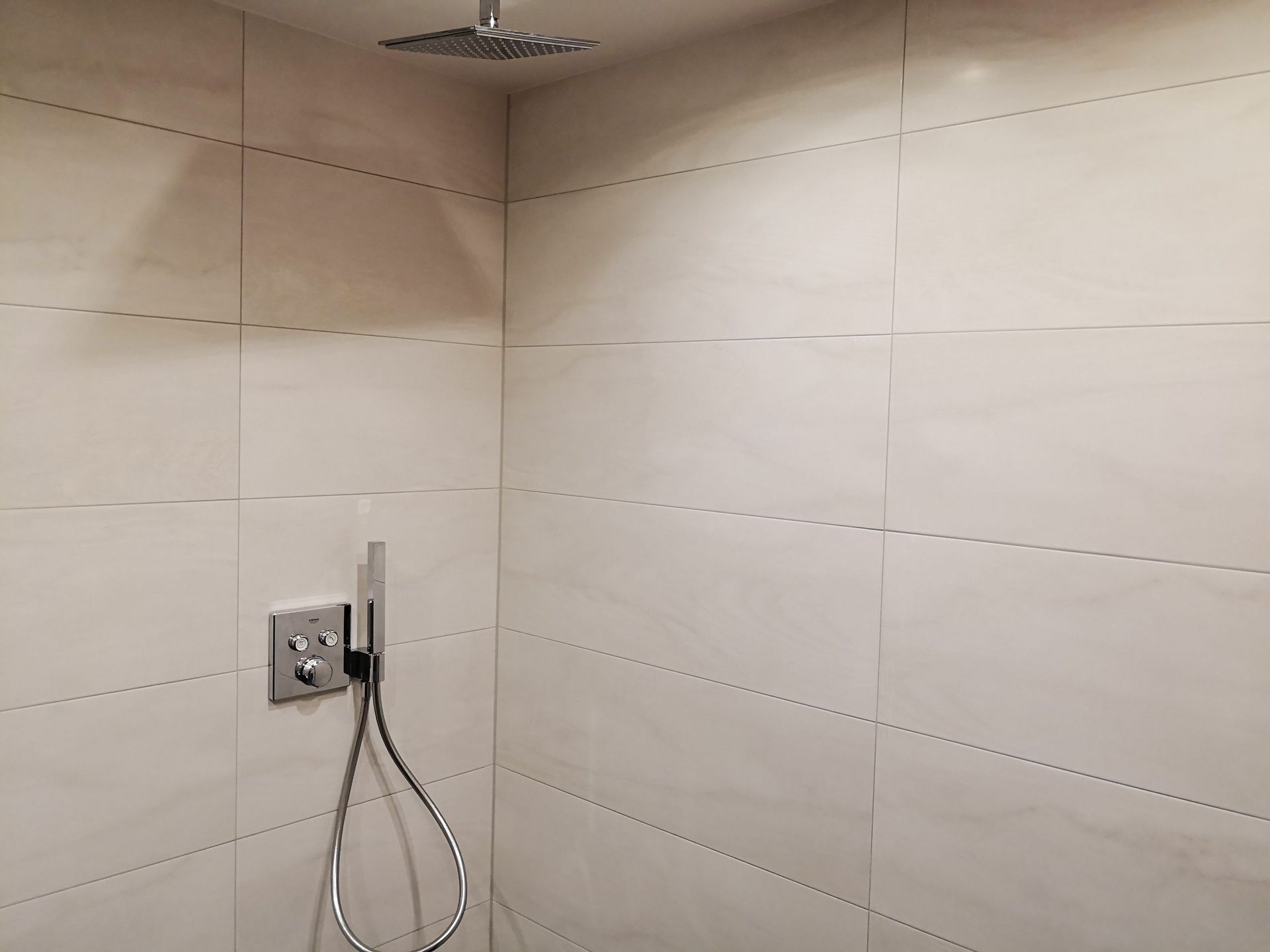 Ein Badezimmer mit weißen Fliesen und einem Duschkopf