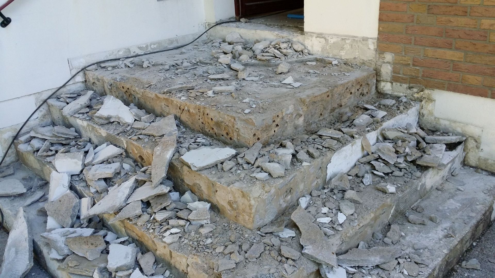 Vor einem Haus wird eine Betontreppe abgerissen.