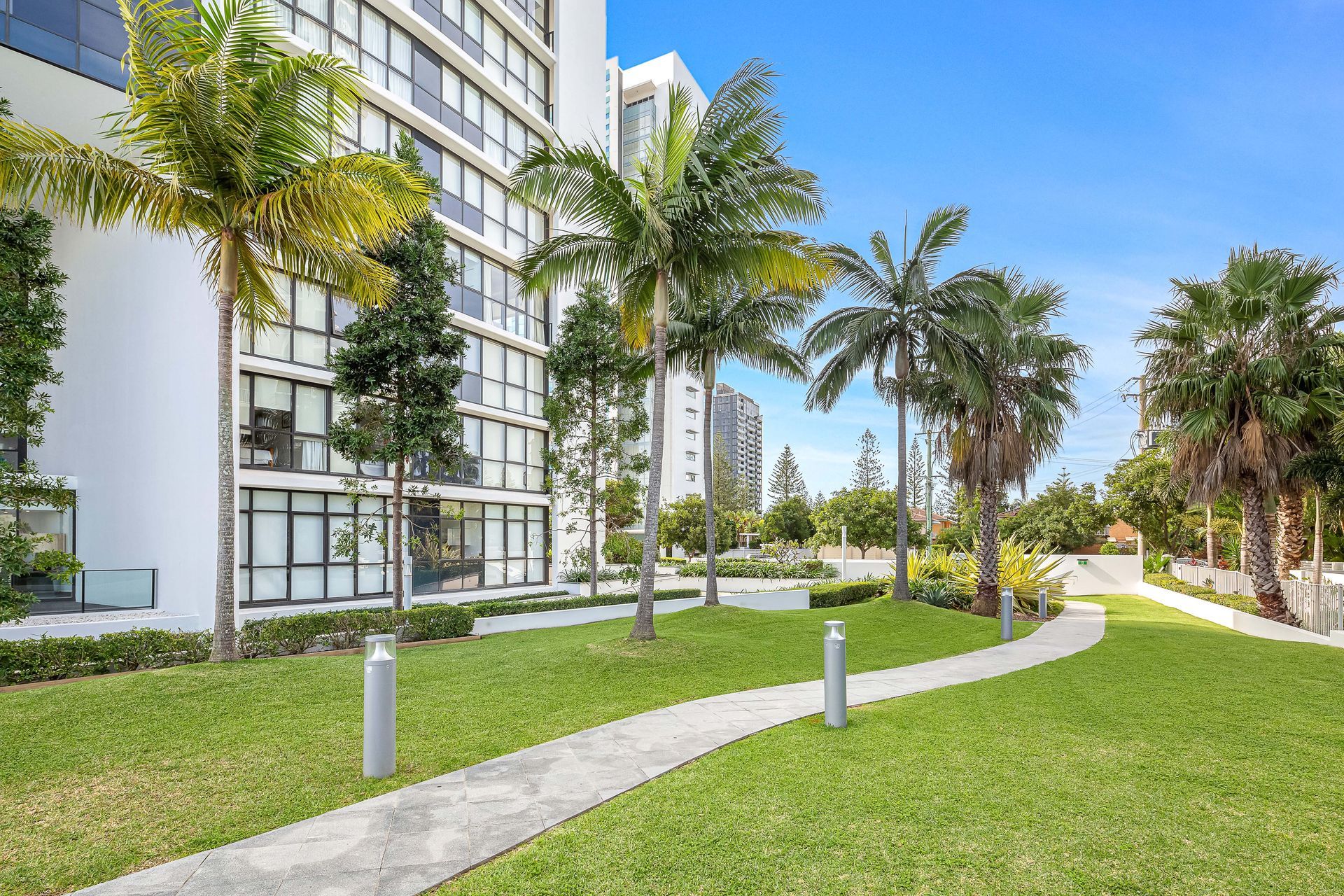 A walkway leading to a building with palm trees in front of it. This is the outdoor common area in the Sierra Grand Resort