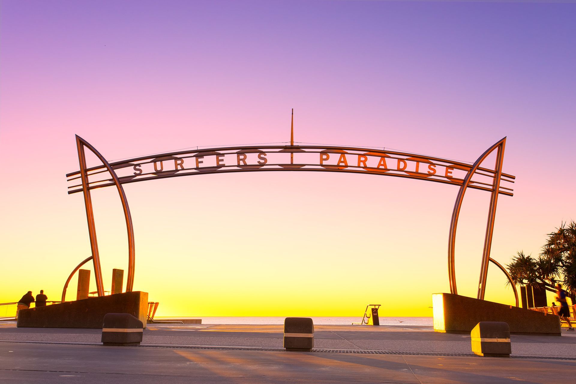 A sunset over a beach with a sign that says surfers paradise