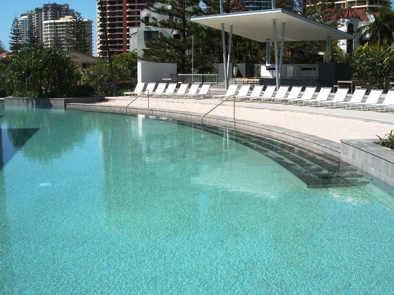 A large swimming pool surrounded by white chairs. Q1 building, Surfers Paradise