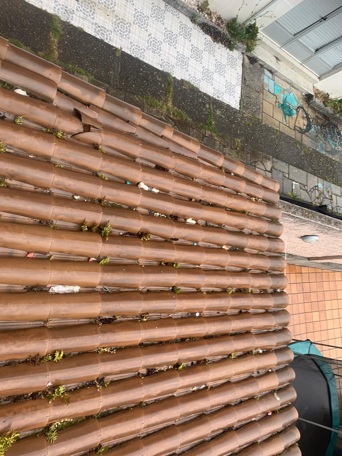 Tejas de terracota colocadas en diagonal junto a una pasarela en la azotea y un borde de grava.