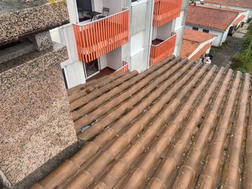 Azoteas con tejas de terracota junto a apartamentos blancos con balcones y contraventanas naranjas.