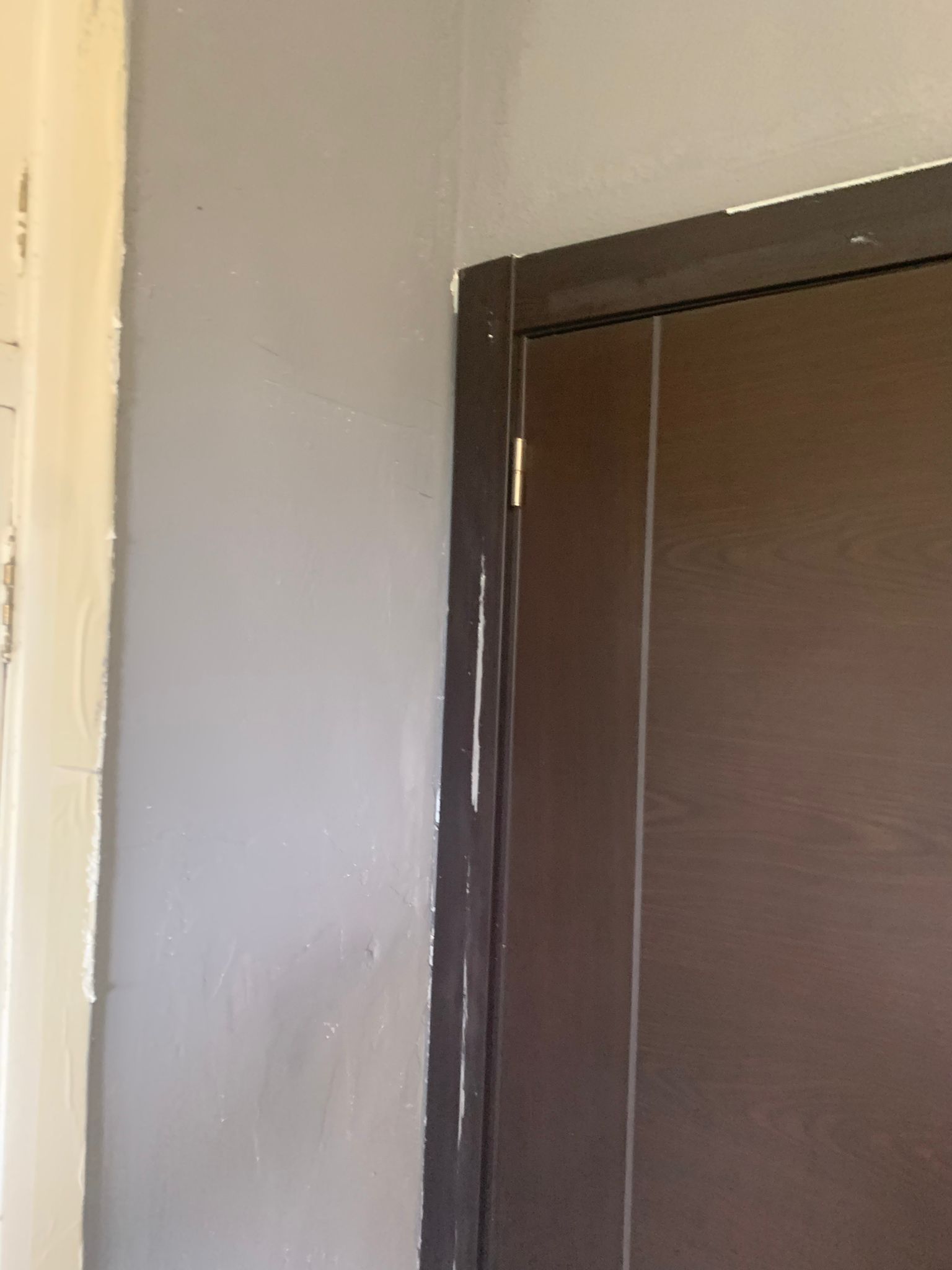 Marco de puerta marrón junto a una pared beige claro, que muestra una puerta en una habitación interior.