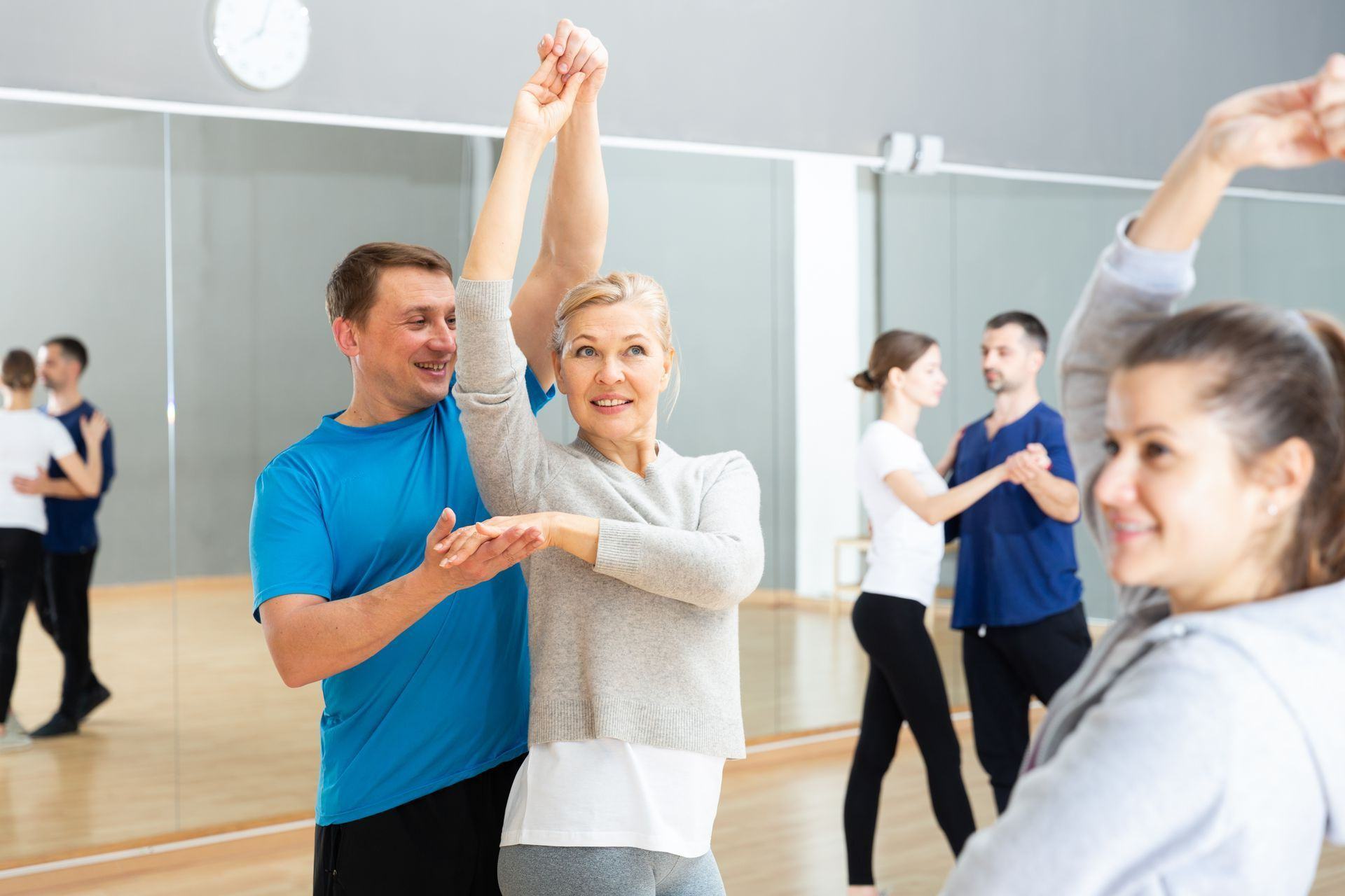 Une femme au cheveux gris sourit er danse ave un homme
