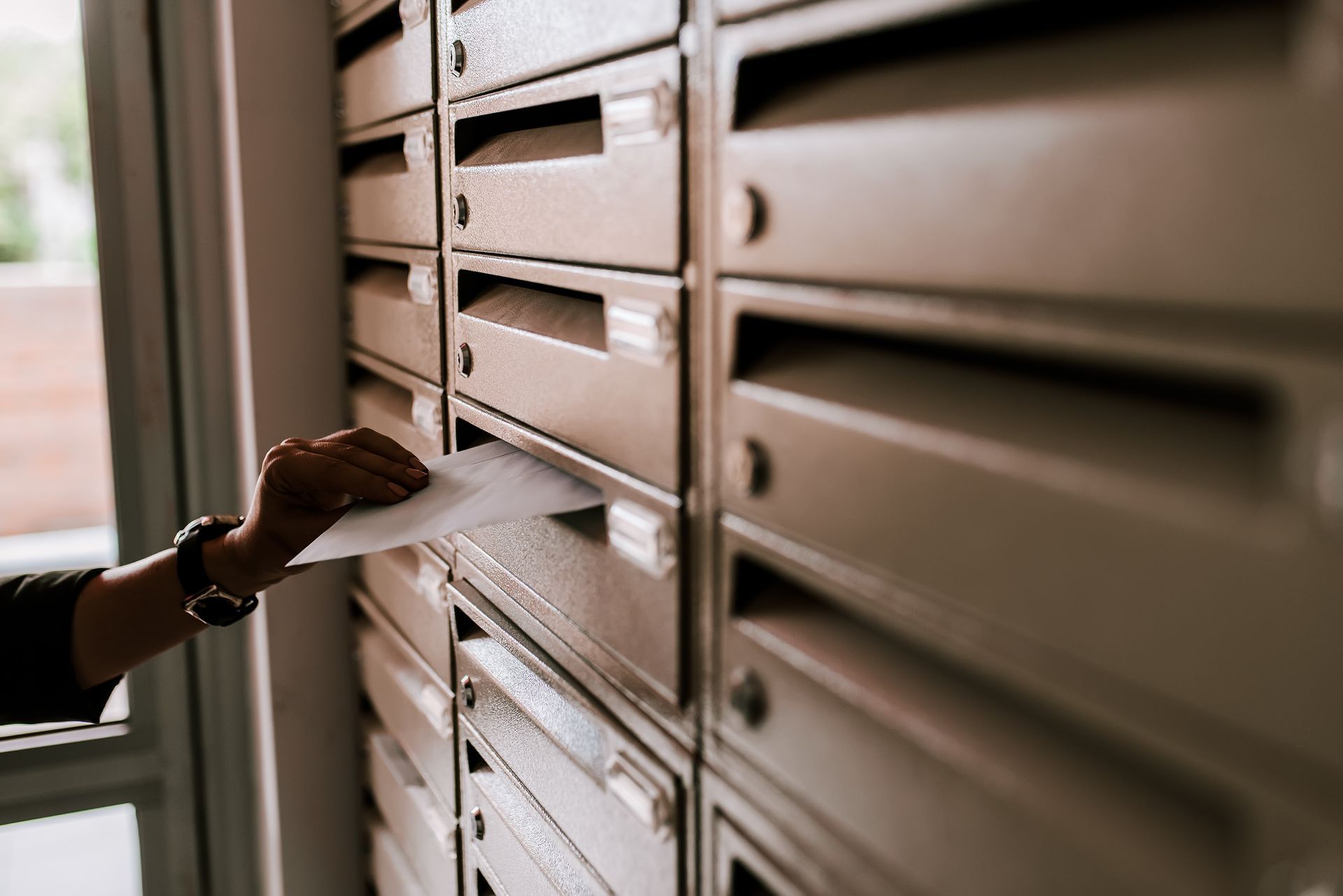 Personne déposant du courrier dans une boîte aux lettres dans un immeuble.