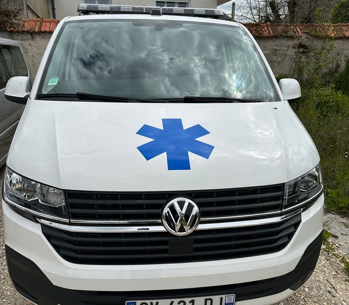 Ambulance avec le sigle de l'étoile bleue de vie sur le capot ; logo VW visible.
