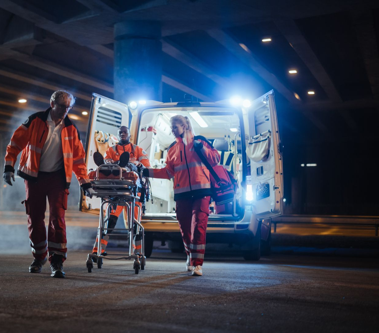 Des secouristes déchargent une civière d'une ambulance de nuit.